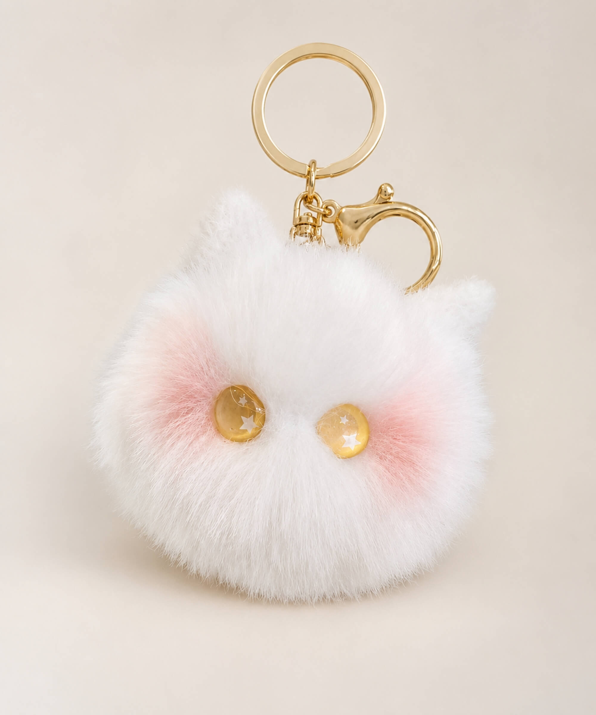 Yellow eye cat plush keychain with white fluffy body, yellow star eyes, pink cheek detail and gold hardware